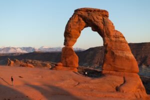 Delicate Arch op een rood rotsplateau onder een heldere blauwe lucht in Arches National Park.