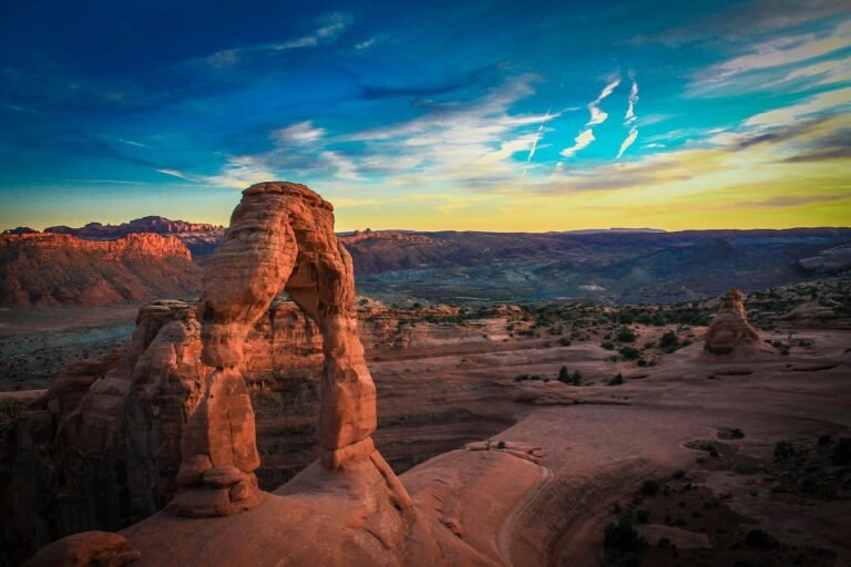 Delicate Arch op een rood rotsplateau onder een heldere blauwe lucht in Arches National Park.