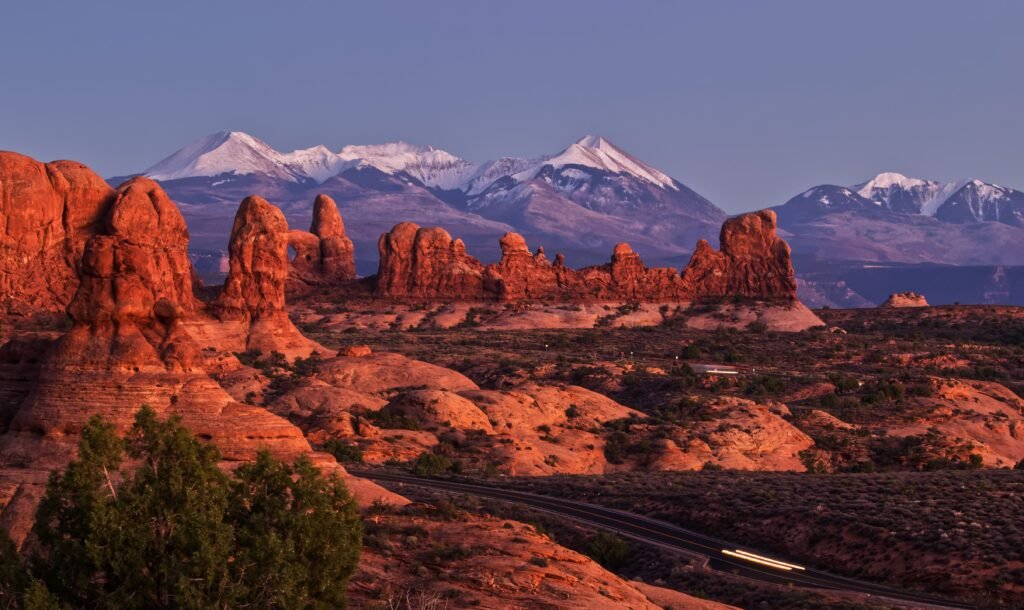 Arches Scenic Drive: Besneeuwde La Sal Mountains zichtbaar achter rode rotsformaties in Arches National Park.