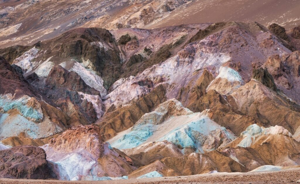 Kleurrijke rotshellingen van Artist’s Palette in Death Valley: zachte roze, groene, paarse en oranje banden in een ruig woestijnlandschap.