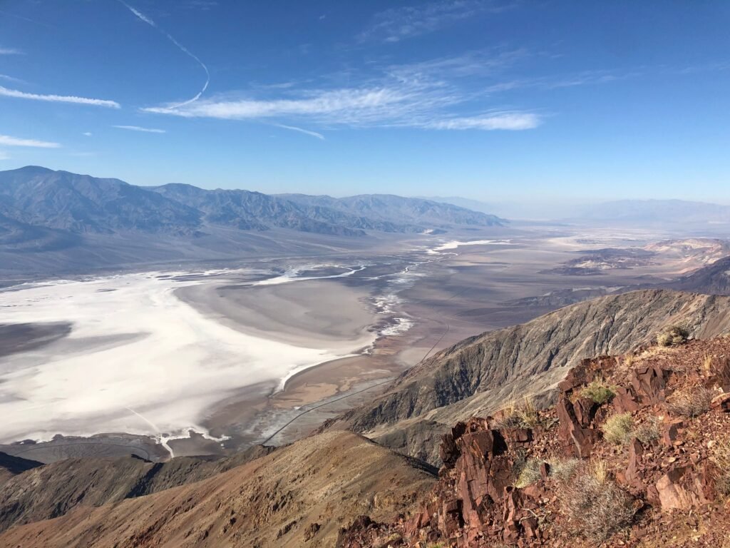 Panoramisch uitzicht vanaf Dante’s View in Death Valley: diep dal met witte zoutvlakte, donkere bergruggen en een heldere woestijnhemel.