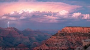 Panoramisch uitzicht vanaf Yavapai Point aan de South Rim van de Grand Canyon met een bliksemschicht die inslaat in de diepe kloof, omringd door donkere onweerswolken.
